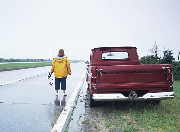 A Woman in a Yellow Jacket Standing Next to a Red Truck | Truck Problems