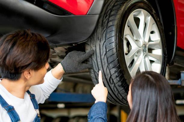 A man and woman are collaborating to fix a car tire